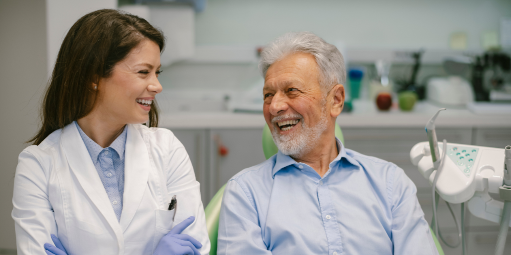 "Senior man smiling and talking with a female dentist in a dental office."