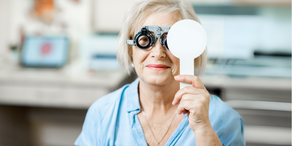 "Senior woman undergoing an eye examination, holding a vision test occluder."