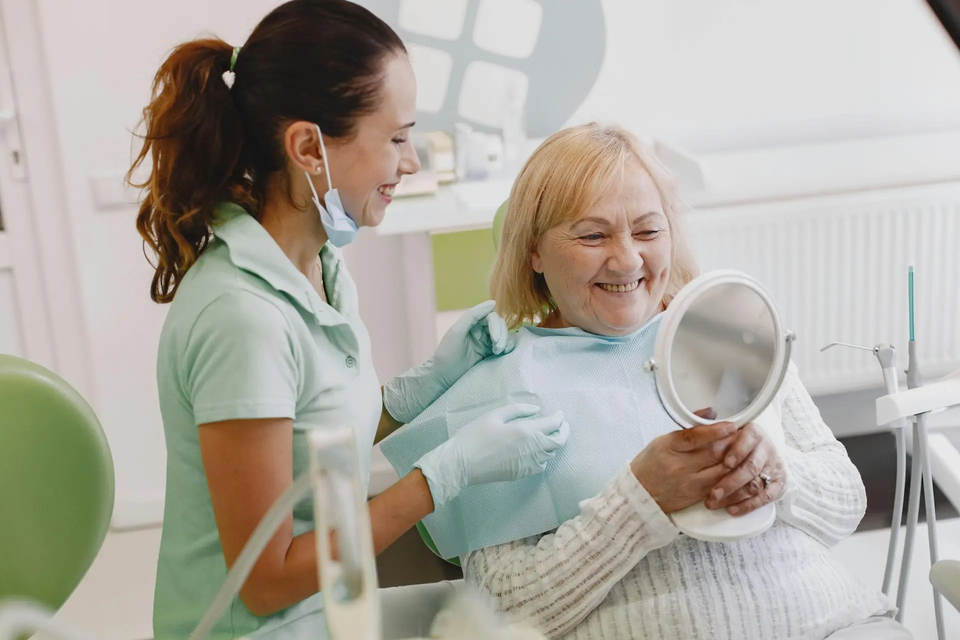 Senior woman smiling during a dental checkup while a dental hygienist assists her at the dentist's office